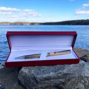 Lobster Trap Wood Pen, made from old, oak lobster traps, that have been retired by Maine lobstermen. It is laying on rocks by the ocean.